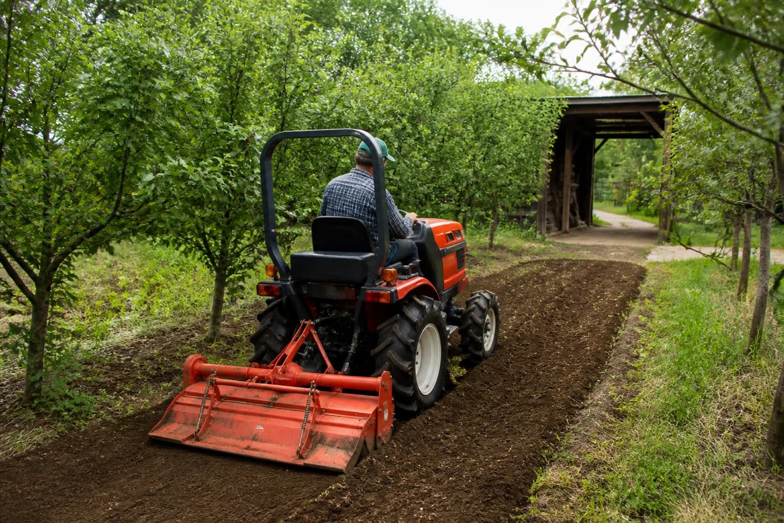 Kompaktný japonský malotraktor pracuje na úzkom pozemku medzi ovocnými stromami.