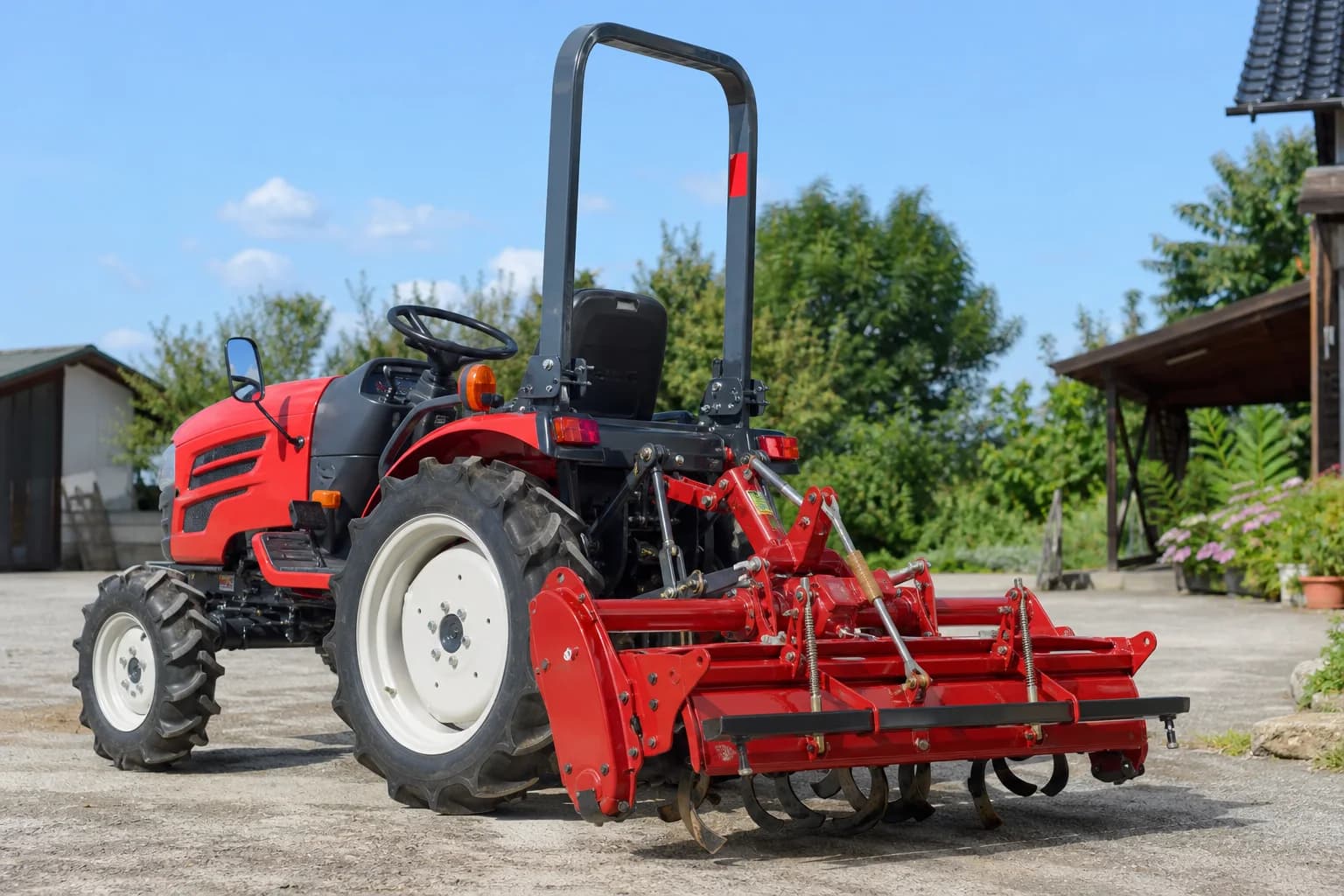 Malotraktor s pripojeným kultivátorom na spevnenom dvore pred nastavením.