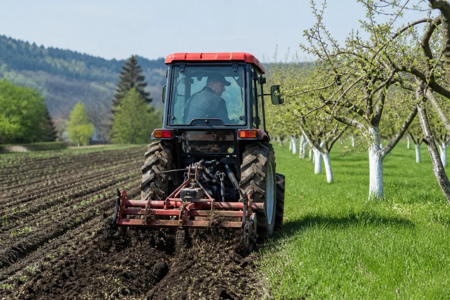 Japonský malotraktor na vidieckom dvore pri poli a sade.