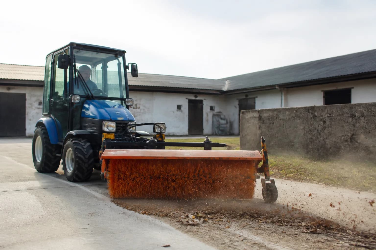 Malotraktor so zametacou kefou čistí spevnenú plochu na dvore.
