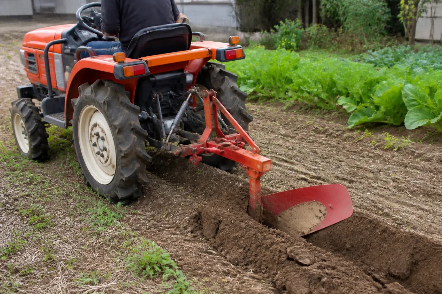 Malotraktor so zapojeným jednoradličným pluhom pri prvej brázde v záhrade.