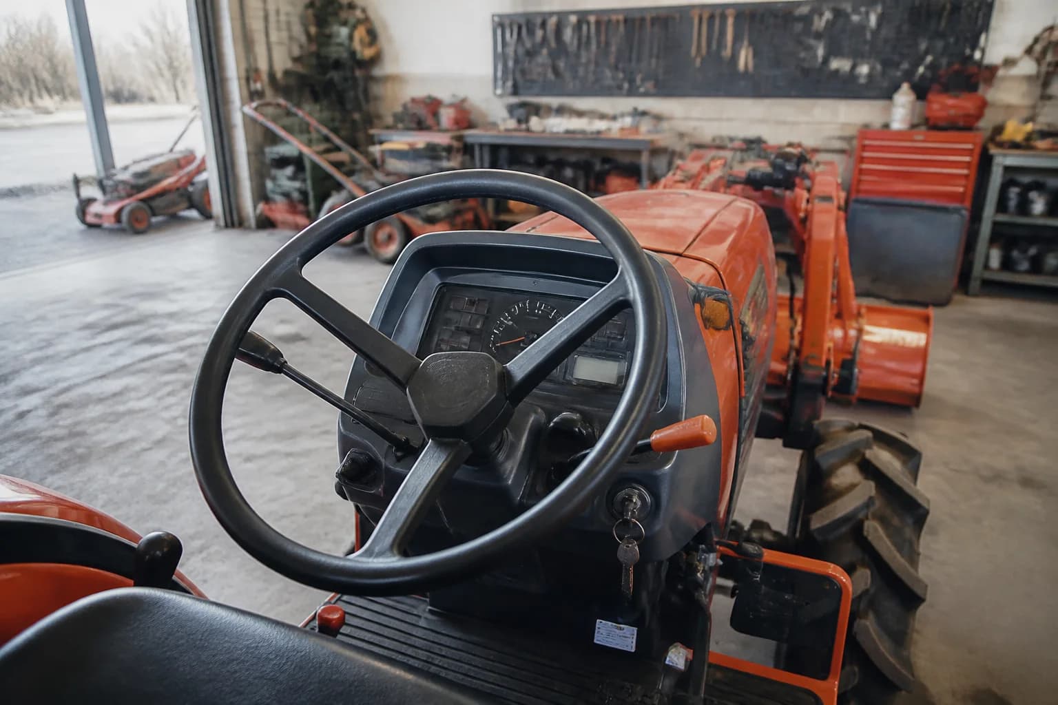Použitý malotraktor v dielni s detailom na palubný panel a počítadlo motohodín.
